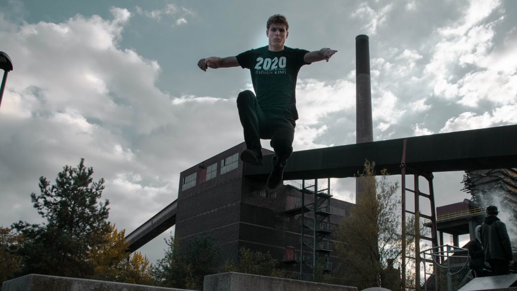 Pit Hantzsche auf einem Stahlgerüst vor bewölktem Himmel beim Parkourtraining auf Zollverein
